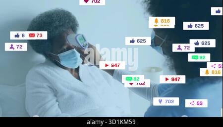 Caregiver measuring masked patient forehead with infrared thermometer at home with media icons Stock Photo