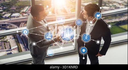 Two business professionals engage in a strategic discussion with digital security icons representing connectivity and technology in a modern office Stock Photo