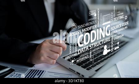 A professional software developer focuses on coding tasks using a laptop, showcasing various programming concepts and terms related to technology and Stock Photo