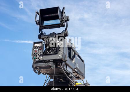 Professional camera on a massive tripod arm against a clear blue sky ready for film and tv production Stock Photo