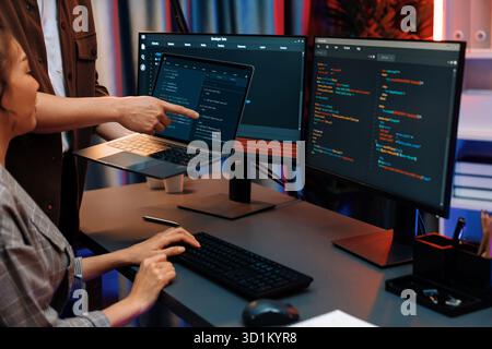 Serious of IT developers discussing intelligent website development coder system running data online two screens with laptop showing information netwo Stock Photo