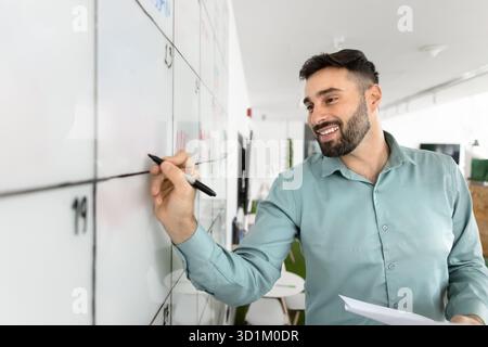 Happy young business professional organize workflow structure on schedule board Stock Photo
