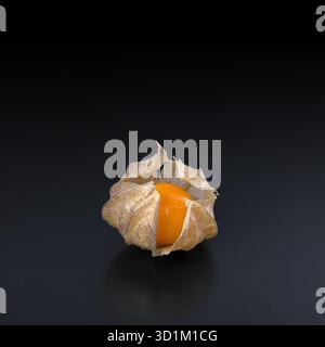 Goldenberry, groundcherry, or poha, front view and close-up, on a black glass plate. Ripe, fresh Physalis peruviana, also called cape gooseberry. Stock Photo