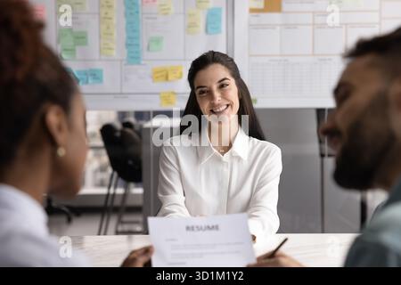 Cheerful confident young businesswoman applicant answering recruiters questions on interview Stock Photo