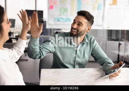 Joyful excited young businessman give high five to female colleague Stock Photo