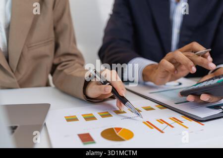 Two business professionals are discussing financial charts and reports in a modern office. They collaborate, share ideas, and analyze data together, h Stock Photo