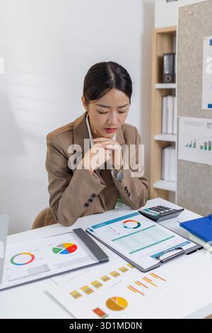 A group of business professionals engaged in a serious office discussion, analyzing financial reports and exchanging ideas to solve problems and make Stock Photo