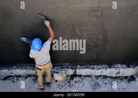 Worker on a concrete wall finition in a construction work site - France Stock Photo
