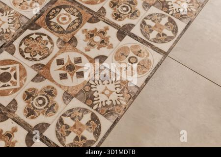 A close-up view of vintage tiles featuring various intricate designs and colors, adding character to the floor. The tiles display a mix of patterns, c Stock Photo