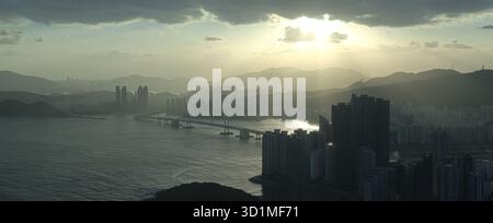 BUSAN, SOUTH KOREA - OCTOBER 9, 2025 - Busan cityscape establishing shot featuring the Gwangandaegyo Bridge over the ocean at sunset Stock Photo