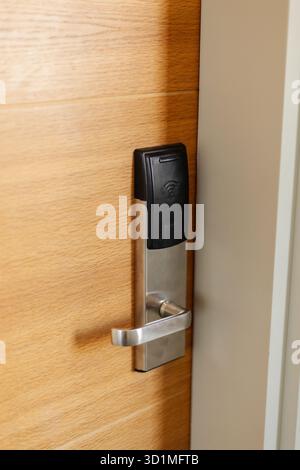 A sleek electronic door lock is installed on a wooden door, showcasing modern technology designed for keyless entry. This lock offers a secure and con Stock Photo