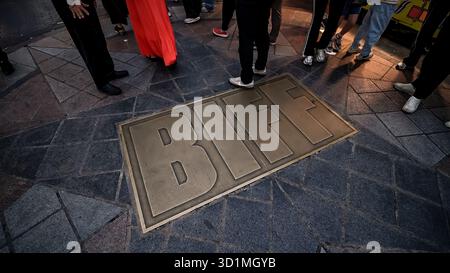 BUSAN, SOUTH KOREA - OCTOBER 10, 2025 - People standing around a brass BIFF plaque embedded in a stone sidewalk in Busan Stock Photo