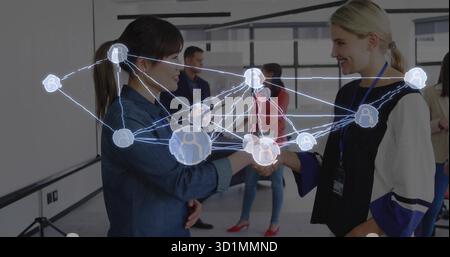 Exchanging handshake between two businesswomen in conference room with digital network overlay Stock Photo