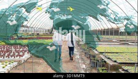 Walking two technicians in lab coats inspecting plants in greenhouse, with trays, map overlay Stock Photo