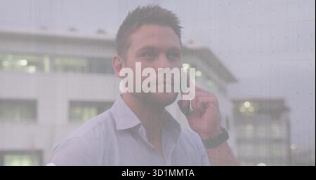 Businessman wearing dress shirt and smartwatch talking on smartphone in front of office building Stock Photo