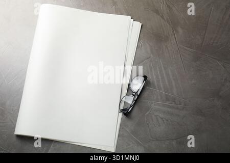 Newspaper and glasses on grey table, flat lay. Mockup for design Stock Photo