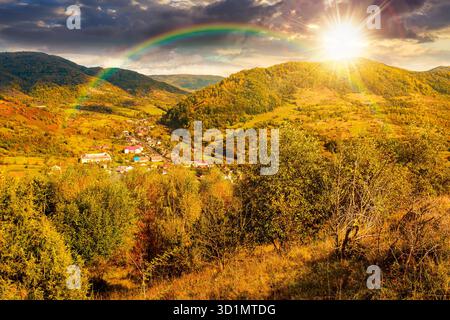 autumn landscape in mountains at sunset. beautiful view of countryside. colorful alps in the background. cloudy sky. picturesque rural scenery with vi Stock Photo