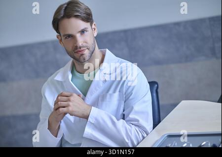 Thinking. Young doctor in a lab coat looking thoughtful Stock Photo