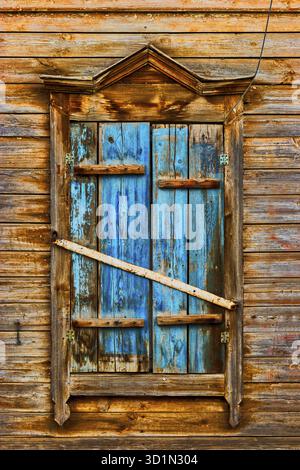 Weathered wooden window in slums painted in peeling blue paint Stock Photo