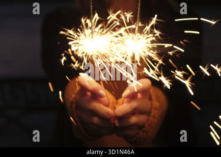 Woman holding a sparkler in her hands on wind, closeup Stock Photo
