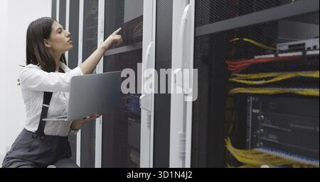 Technician performing maintenance tasks in a server room rack Stock Photo