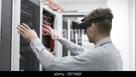 Young IT engeneer using virtual reality headset over server room background Stock Photo