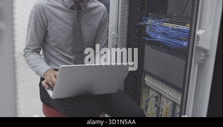 Technician performing maintenance tasks in a server room rack Stock Photo