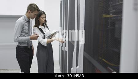 Technicians using laptop while analyzing server in server room Stock Photo