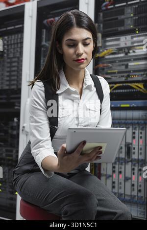 Technician apecialist woman using laptop while analyzing server in server room Stock Photo
