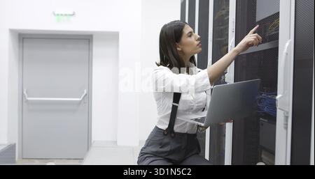 Technician performing maintenance tasks in a server room rack Stock Photo