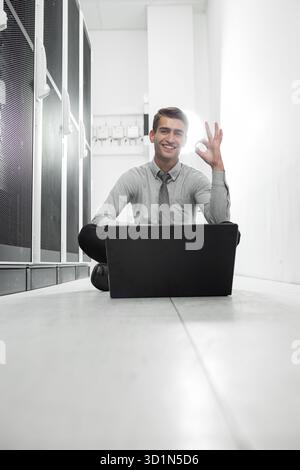 Portrait of modern young man holding laptop standing in server room working with supercomputer Stock Photo