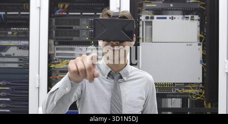Young IT engeneer using virtual reality headset over server room background Stock Photo