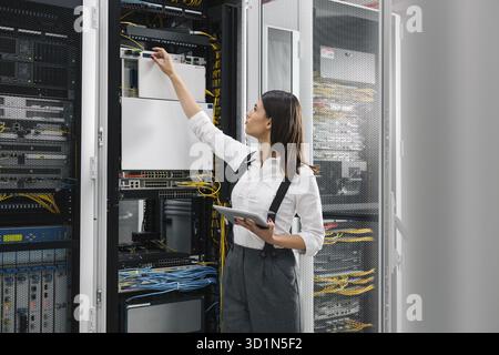 Technician using tablet pc while analysing server in large data center Stock Photo