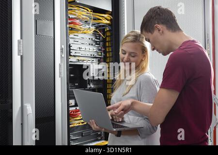 Team of technicians working together on servers at the data centre Stock Photo