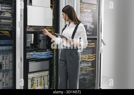 Technician using tablet pc while analysing server in large data center Stock Photo