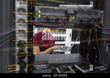 Portrait of modern young man holding laptop standing in server room working with supercomputer Stock Photo