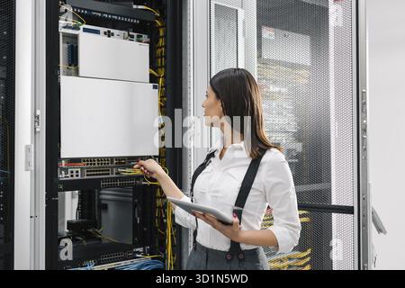 Technician using tablet pc while analysing server in large data center Stock Photo