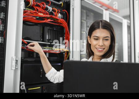 Portrait of technician working on laptop in server room Stock Photo