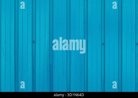 Turquoise sheet metal wall with vertical corrugations evenly spaced creating, series of narrow parallel ridges with horizontal line connecting screws. Stock Photo