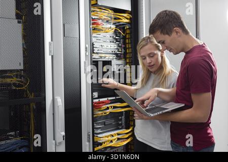 Team of technicians working together on servers at the data centre Stock Photo