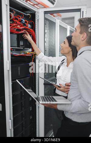 Team of technicians working together on servers at the data centre Stock Photo