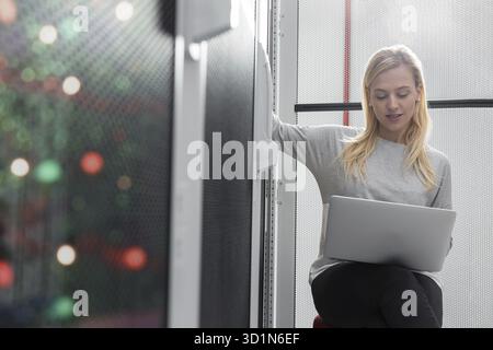 Portrait of technician working on laptop in server room Stock Photo