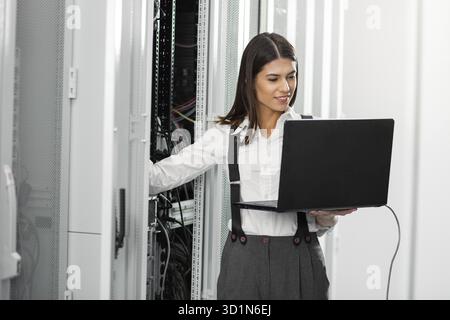 Portrait of technician working on laptop in server room Stock Photo