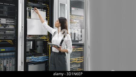 Technician using tablet pc while analysing server in large data center Stock Photo