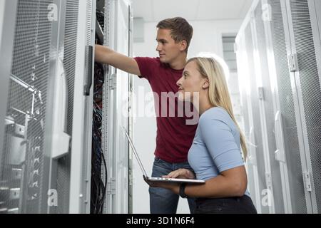 Team of technicians working together on servers at the data centre Stock Photo