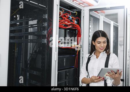 Technician using tablet pc while analysing server in large data center Stock Photo