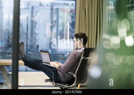 Full length side view of businessman using computer at desk in office Stock Photo