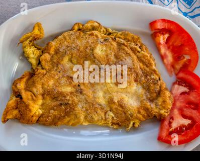 An Omelette Served With Tomato Wedges. A Simple Dish Made From Beaten Eggs And Fried In A Pan. It Can Be Prepared Plain Or With Various Fillings Such Stock Photo