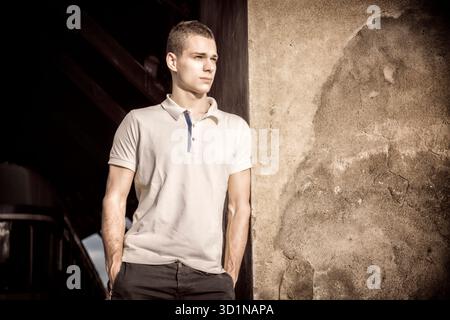 Attractive green eyed young man leaning against wall outside Stock Photo