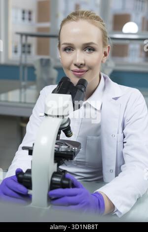 Science, chemistry, technology, biology and people concept - close up of female scientist looking to microscope in clinical laboratory Stock Photo